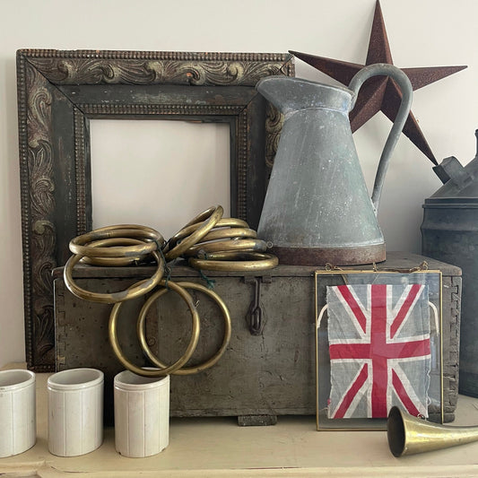 an eclectic mix of vintage and antique items, a collection of curated vintage telling a story of the home, a vintage union jack in brass frame, picks up on the antique hunting horn and beautiful oversized brass curtain rings.